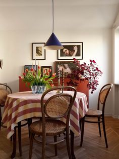 a dining room table with flowers in a vase on the top and chairs around it