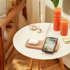 a cell phone sitting on top of a white table next to an orange vase and cup