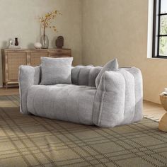 a grey couch sitting on top of a rug in a living room next to a window