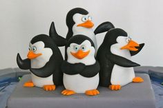 a group of penguins standing on top of a cake