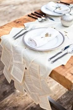 a wooden table topped with white plates and silverware