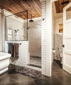 a bathroom with a walk in shower next to a white toilet and sink under a wooden ceiling