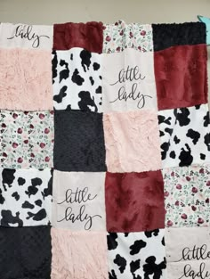 a quilt with words written on it and black, red, white and pink squares