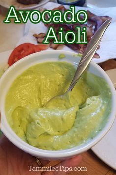 avocado dip in a white bowl with a spoon sticking out of the top