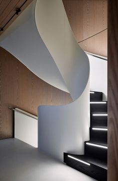 a white staircase with black handrails next to a wooden wall