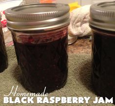 three jars filled with black raspberry jam on top of a towel covered counter