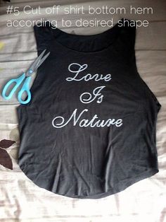 a black shirt that says love is nature with scissors on the bed next to it