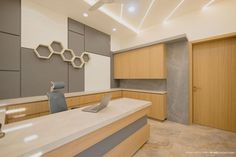 an empty office with wooden cabinets and white counter tops, along with a laptop on the desk