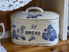 a blue and white bread box sitting on top of a wooden shelf