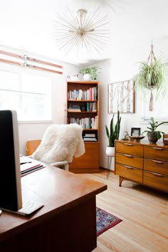 a room with a computer, bookshelf and plants on the shelves in it