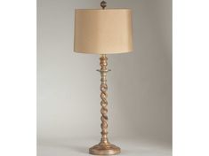 a lamp that is on top of a white surface with a beige shade over it