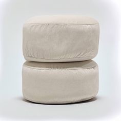 two round cushions sitting on top of each other in front of a white background,