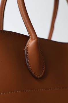 Height - 11in Width - 15.4in Genuine Leather Crafted from high-quality materials, the Efimia bag boasts a luxurious finish and exceptional durability. The sleek silhouette is enhanced with sophisticated detailing, including polished hardware and meticulous stitching, ensuring a chic and refined appearance. High-end Brown Bags With Leather Handles, High-end Brown Bag With Leather Handles, Brown Textured Leather Shopping Bag, High-end Brown Box Bag With Leather Handles, Brown Double Handle Bag With Gold-tone Hardware, Winter Sandals, Casual High Heels, Strappy Pumps, Wedge Loafers