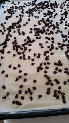 chocolate chips sprinkled on top of white frosting in a baking pan, ready to go into the oven