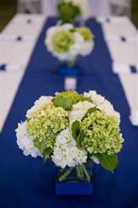 there are many flowers in the vases on this long blue table runner that is decorated with white hydrangeas and greenery