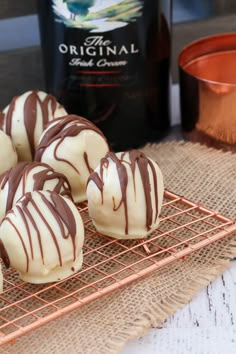 chocolate covered donuts on a cooling rack next to a bottle of wine