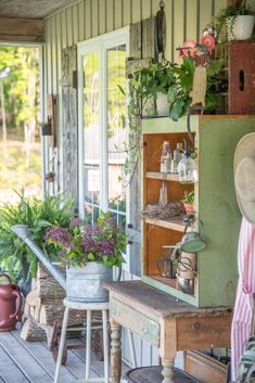 a porch with potted plants on it and an old fashioned cabinet in the corner