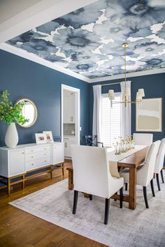 the dining room is decorated in blue and white with clouds painted on the ceiling above it