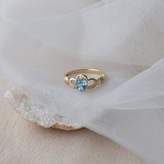 Delicate and symbolic Claddagh ring is made out of 14k solid gold and set with blue heart topaz and diamond It would make a perfect choice for the engagement or as a push gift. Ring can be made in white, rose or yellow 14k gold. Highly polished. If you want to customise this product or set it with another stones - please write to us. ❤ Hand Made with love in our studio in Prague ❤ Stone details Topaz Shape: Heart Dimensions: 5.7 mm Color: Blue Origin: Natural Diamond Amount: 1 Shape: Round Color Topaz Birthstone Promise Ring Fine Jewelry, Topaz Birthstone Promise Ring In Fine Jewelry Style, Fine Jewelry Topaz Birthstone Promise Ring, 14k Gold Topaz Birthstone Ring Fine Jewelry, 14k Gold Topaz Ring With Accent Stones For Promise, 14k Gold Topaz Birthstone Ring, Blue Topaz Diamond Promise Ring With Birthstone, Heart Cut Topaz Birthstone Ring For Anniversary, 14k Gold Topaz Birthstone Promise Ring