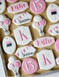 decorated cookies with pink and white icing are in a box for a birthday party