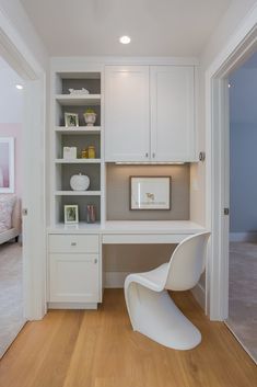 a white desk and chair in a room with wooden floors, built - in cabinets and drawers