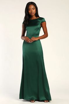 a woman in a green dress posing for the camera with her hands on her hips