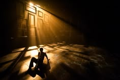 a person sitting on the floor in front of a window with light streaming through it