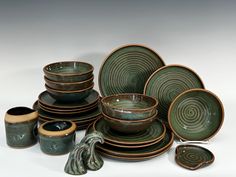 a collection of green and brown dishes, cups and saucers on a white background