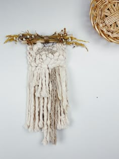 a woven wall hanging next to a wicker basket with twigs on it and a dried twig