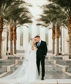 a bride and groom standing in front of palm trees