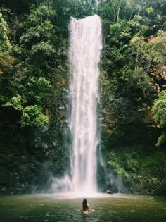 a woman swimming in front of a waterfall