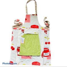 an apron is hanging on the back of a white and red kitchen towel with green trim