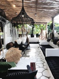 a living room filled with lots of furniture and hanging plants on the ceiling above it