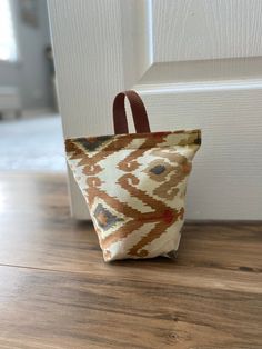 a brown and white bag sitting on top of a wooden floor next to a door