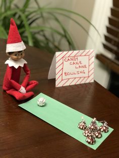 an elf is sitting on a table next to a sign