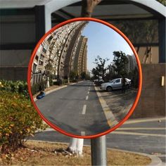 a mirror that is on the side of a pole in front of a street with cars