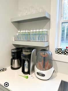 a coffee maker sitting on top of a counter next to a shelf filled with bottles