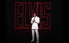 a man standing on top of a stage in front of a red sign that says give