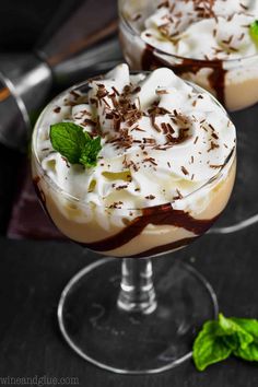 two desserts with chocolate and whipped cream on top are sitting on a glass plate