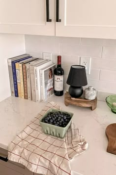 a kitchen counter with a bowl of blueberries and a bottle of wine