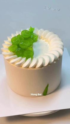 a cake with white frosting and green leaf decoration on top, sitting on a plate