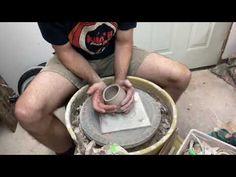 a man is sitting on the floor working on a piece of concrete with his hands