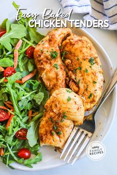 a white plate topped with chicken and salad next to a fork on top of a table