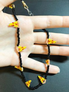 a hand holding a black beaded necklace with yellow flowers