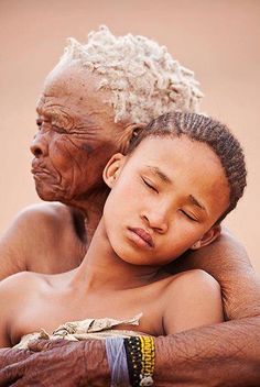 an older man holding a young boy in his arms and the child is sleeping on top of him