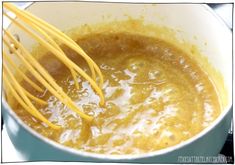 a pot filled with yellow liquid and whisks