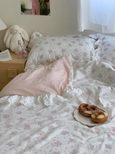 two donuts on a plate sitting on a bed with pink and white floral sheets