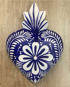 a blue and white heart shaped vase sitting on top of a wooden table next to a wall