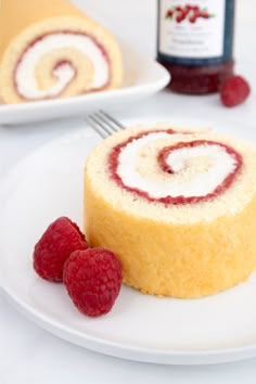 there is a roll on the plate with raspberries next to it