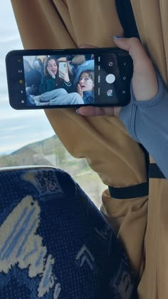 a person holding up a cell phone to take a selfie in front of a window